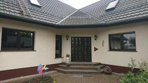 une maison avec une porte noire et un cerf-volant sur la terrasse couverte dans l'établissement Ferienwohnung Spreewald Betty, à Werben