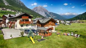 a group of people sitting in a field with a playground at Rosengarden Alpine Residence in Valdidentro