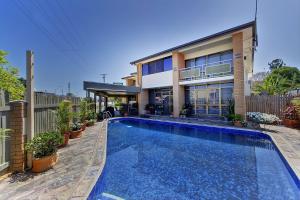 una casa con piscina frente a una casa en Raintree Motel en Townsville