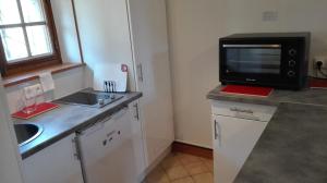 a small kitchen with a sink and a microwave at La Longère aux Volets Rouges, Meublé Tourisme 2 étoiles in Maillebois