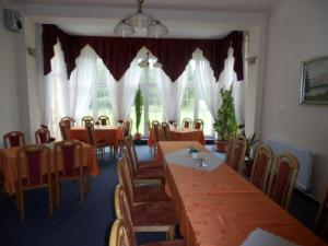 a dining room with tables and chairs and windows at Penzion u Zámku in Habartov