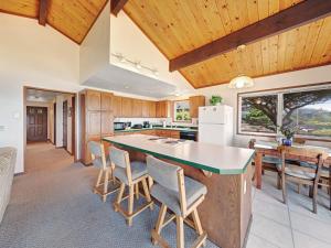 una cucina con soffitti in legno e una grande isola con sedie di Ocean Waves a Gleneden Beach