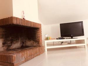 a living room with a tv and a brick fireplace at Mansardina in centro in Tagliacozzo