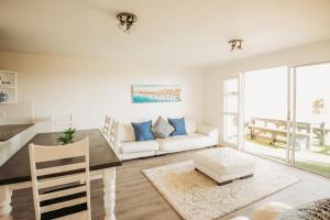 uma sala de estar com uma mesa e um sofá em Voir la Mer - Blouberg Beach em Bloubergstrand