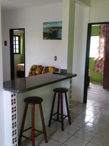 a kitchen with a counter and two bar stools at Moradas Jeane in Guarda do Embaú