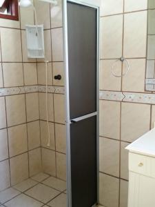 a shower with a black door in a bathroom at Moradas Jeane in Guarda do Embaú +40 photos