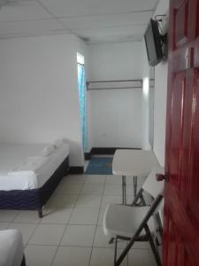 een slaapkamer met een bed, een stoel en een deur bij Hostal Don Frank in San Carlos
