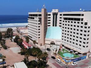 a large building next to the beach and the ocean at Hotel Corona Plaza in Rosarito