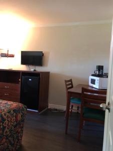 a hotel room with a desk and a table with a microwave at Sierra Crossing Motel in Bloomington