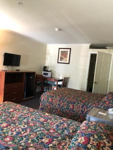 ein Hotelzimmer mit 2 Betten und einem Schreibtisch in der Unterkunft Sierra Crossing Motel in Bloomington