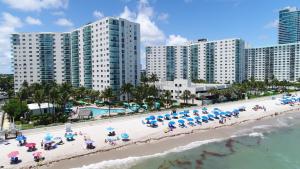 a group of people sitting on a beach with umbrellas at Hollywood Condos in Hollywood