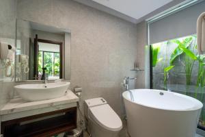 ein Badezimmer mit einer Badewanne, einem WC und einem Waschbecken in der Unterkunft Khong Cam Garden Villas in Hoi An
