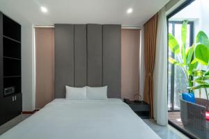a bedroom with a white bed and a large window at Khong Cam Garden Villas in Hoi An