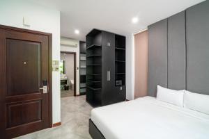 a bedroom with a white bed and a black cabinet at Khong Cam Garden Villas in Hoi An