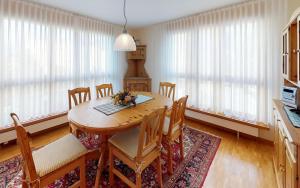 a dining room with a table and chairs and windows at Surpunt 44 in St. Moritz