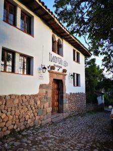 a white building with a door and a brick wall at Inka Tambo Hacienda in Cusco