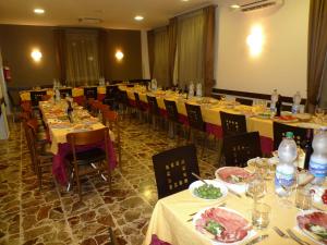 un comedor con mesas y sillas con platos de comida en Hotel de Meis, en Capistrello