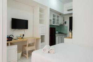 a bedroom with a bed and a desk and a tv at Best Price Studio at Casa De Parco Apartment By Travelio in Tangerang