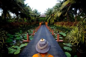 a person is walking down a wooden bridge over a pond at Anantara Bophut Koh Samui Resort in Bophut