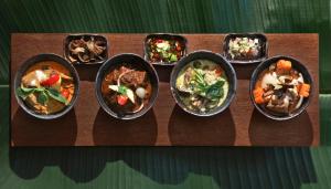 a group of bowls of food on a wooden table at Anantara Bophut Koh Samui Resort in Bophut