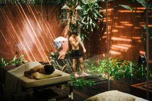 a man laying on a bed next to a man in a shower at Anantara Bophut Koh Samui Resort in Bophut