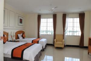 a hotel room with two beds and a chair at Khách sạn SAO NAM in Cao Lãnh