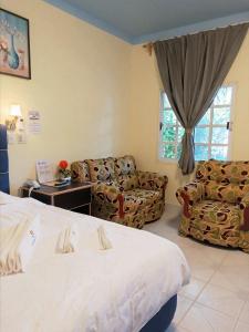 a hotel room with a bed and couches and a window at Sunshine View Hotel and Restaurant in Corozal
