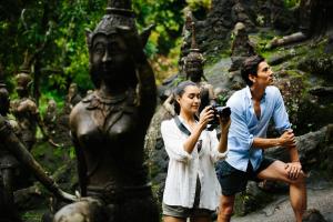 a man and a woman taking a picture of a statue at Anantara Bophut Koh Samui Resort in Bophut
