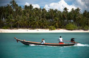two people on a boat in the water near a beach at Anantara Bophut Koh Samui Resort in Bophut