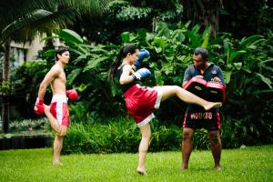 a woman is standing in the grass with boxing gloves at Anantara Bophut Koh Samui Resort in Bophut