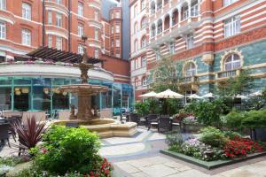 um pátio com uma fonte, cadeiras e edifícios em St. James' Court, A Taj Hotel, London em Londres