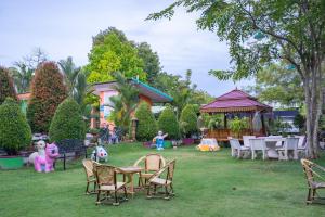 un giardino con tavoli, sedie e gazebo di บ้านทิพรัตน์ สัตหีบ a Sattahip