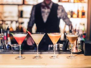 a group of four cocktails on a bar with a bartender at Mercure Toulouse Centre Saint-Georges in Toulouse