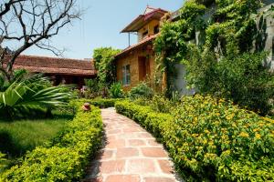 a brick path in front of a house with yellow flowers at Tam Coc Palm House in Ninh Binh