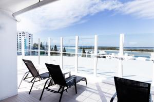 a patio area with chairs, tables, and a balcony at Ocean Views Resort Caloundra in Caloundra