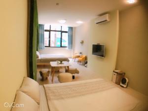 Zimmer mit einem Bett und einem Wohnzimmer mit einem Tisch in der Unterkunft Greenonly Homestay in Tainan