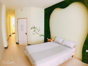 ein Schlafzimmer mit einem weißen Bett mit einem grünen Kopfteil in der Unterkunft Greenonly Homestay in Tainan