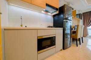 una cocina con estufa y refrigerador en Spacious Studio Room at Capitol Suites Apartment By Travelio, en Yakarta