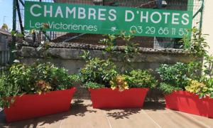 a sign for chambres studios with plants in red pots at Les Victoriennes in Verdun-sur-Meuse