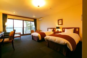 a hotel room with two beds and a window at Tsumugi in Hakone