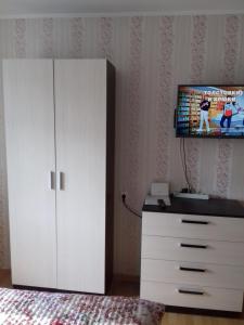 ヴェリーキー・ノヴゴロドにあるTimura Frunze-Olovyanka Apartmentのベッドルーム(テレビ付)、白いキャビネットが備わります。