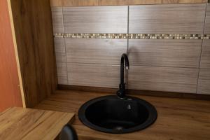 baño con lavabo negro y suelo de madera en Deluxe dreams & spa en Šabac