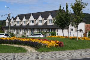 duży biały budynek z ogrodem kwiatów w obiekcie Platán Apartmanház w mieście Balatongyörök