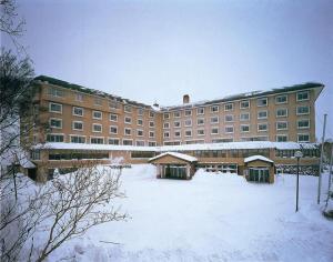 a large building with a lot of snow in front of it at Shiga Park Hotel in Yamanouchi