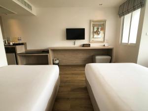 a room with two beds and a desk with a tv at Methavalai Residence Hotel in Bangkok