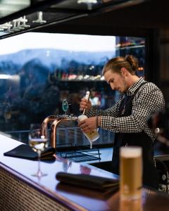 a man is standing at a counter pouring a drink at Elk at Falls in Falls Creek
