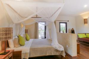 a bedroom with a white bed with a canopy at Jambiani Villas in Jambiani