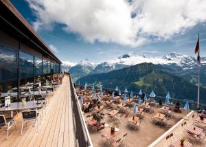 a deck with tables and chairs with mountains in the background at Berghotel Schynige Platte in Wilderswil