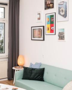 ein Wohnzimmer mit einem blauen Sofa und Bildern an der Wand in der Unterkunft Spittelau Chillout Lounge upto7P spacious bright contactless24h in Wien