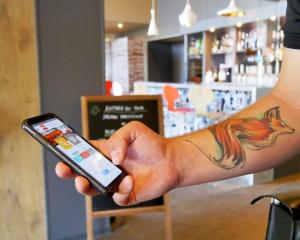 a person holding a cell phone with a tattoo on their wrist at ibis Avranches Mont St Michel in Saint-Quentin-sur-le-Homme